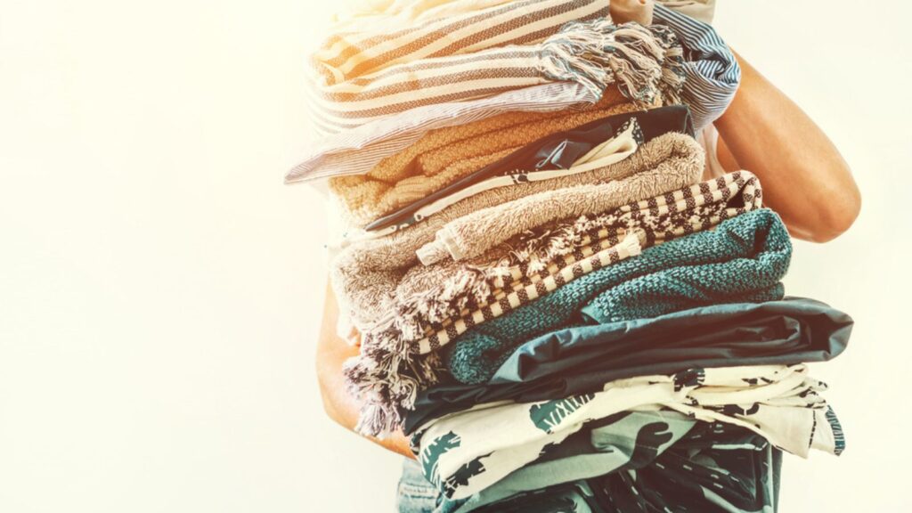Woman takes in hands big pile blue and beige Long Neglected clothes