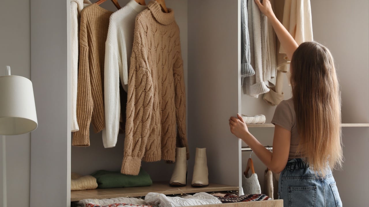 Woman taking warm sweater in wardrobe