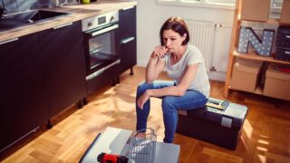 Worried woman sitting on a toolbox during renovating kitchen